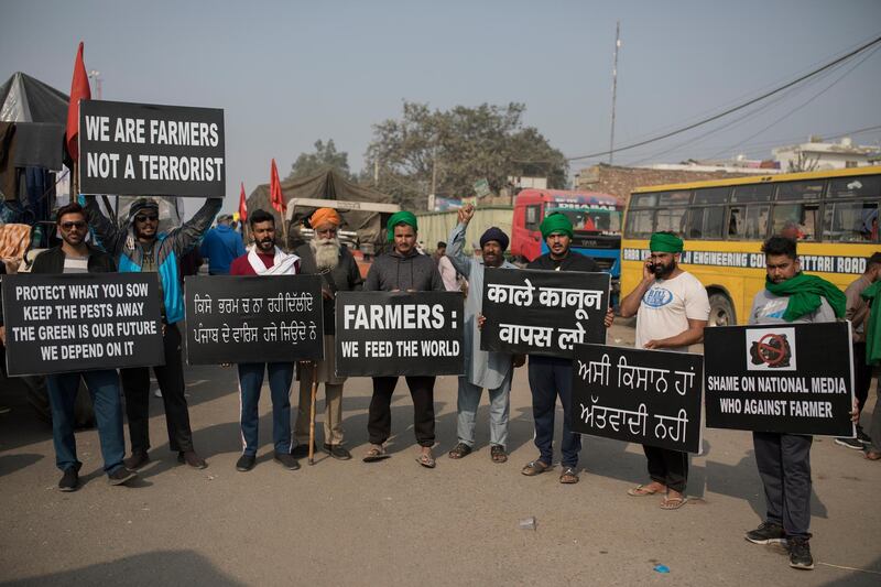 Protesting farmers hold placards at the border between Delhi and Haryana state.  Talks between protesting farmers and the Indian government failed.  AP