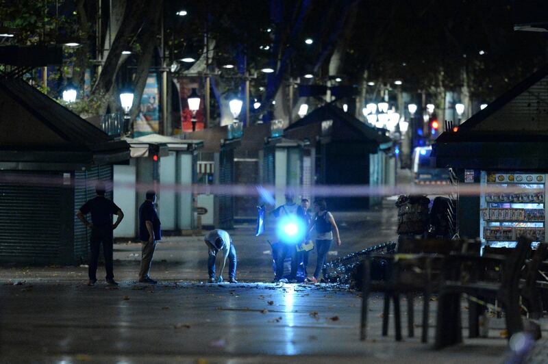 TOPSHOT - Policemen check the area after towing away the van which ploughed into the crowd, killing at least 13 people and injuring around 100 others on the Rambla in Barcelona, on August 18, 2017.
A driver deliberately rammed a van into a crowd on Barcelona's most popular street on August 17, 2017 killing at least 13 people before fleeing to a nearby bar, police said. 
Officers in Spain's second-largest city said the ramming on Las Ramblas was a "terrorist attack". The driver of a van that mowed into a packed street in Barcelona is still on the run, Spanish police said. / AFP PHOTO / Josep LAGO