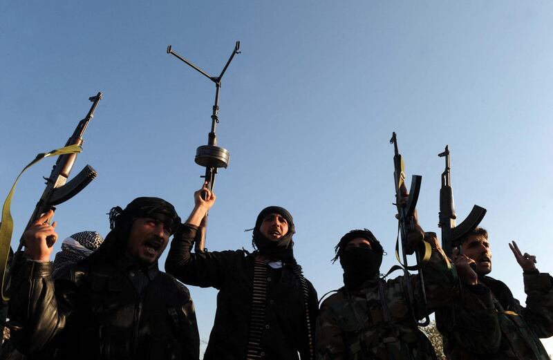 Members of the Free Syrian Army raise their weapons during a patrol in Idlib in northwestern Syria on February 18, 2012. A senior Chinese envoy called for all sides in Syria to stop the violence and for elections to go ahead peacefully after Damascus talks with President Bashar al-Assad, state media said. AFP PHOTO/BULENT KILIC (Photo by BULENT KILIC / AFP)