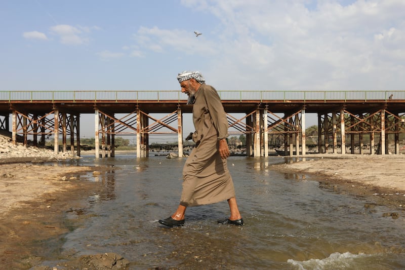 A man crosses the Abu Lehya river, which suffers from drought-induced drop in the water levels, in the Dhi Qar province on March 6, 2023. AFP