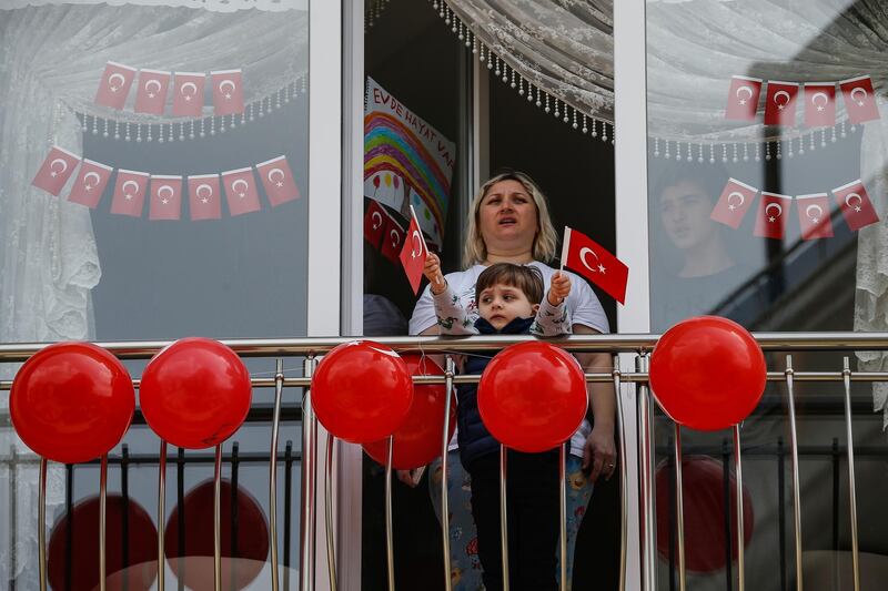 Local residents, in their flat due to the coronavirus, watch celebrations ahead of the National Sovereignty and Children's Day, in Istanbul.  AP