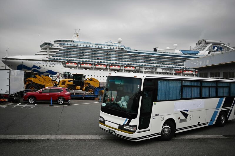 A bus with a driver wearing full protective gear departs from the dockside next to the Diamond Princess cruise ship in Yokohama. AFP