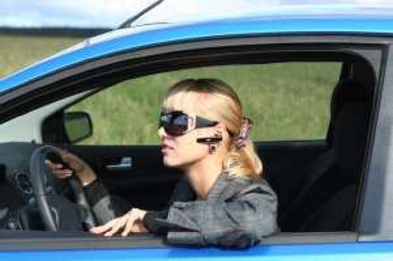 young blond woman in a blue car in sun-glasses with hands free bluetooth