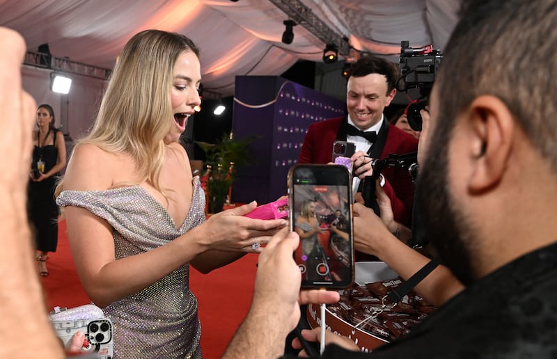 Margot Robbie, the Hollywood actress from Australia, gasps after being given a packet of Tim-Tam chocolate biscuits, on the Red Carpet for the 2024 Australian Academy of Cinema and Television Arts Awards, in Queensland. EPA
