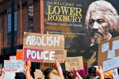 Protesters march by a photo of Frederick Douglas, a historic abolitionist, during a Juneteenth protest and march in honor of Rayshard Brooks and other victims of Police Violence in Boston, Massachusetts on June 22, 2020. / AFP / Joseph Prezioso
