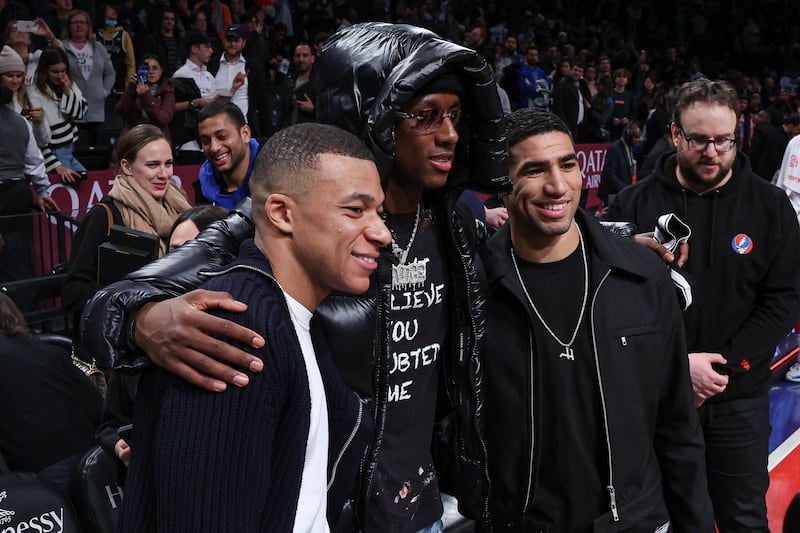 Jan 2, 2023; Brooklyn, New York, USA; Paris Saint-Germain and French national forward Kylian Mbappe (left) and PSG teammate defender Achraf Hakimi (right) pose for a photo with New York Jets cornerback Sauce Gardner (center) after the game between the Brooklyn Nets and the San Antonio Spurs at Barclays Center.  Mandatory Credit: Vincent Carchietta-USA TODAY Sports
