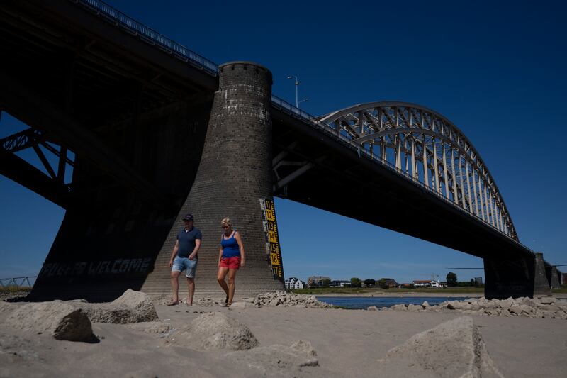 People take a stroll on the river bed of the Waal as water levels dropped because of drought in Nijmegen, Netherlands. AP