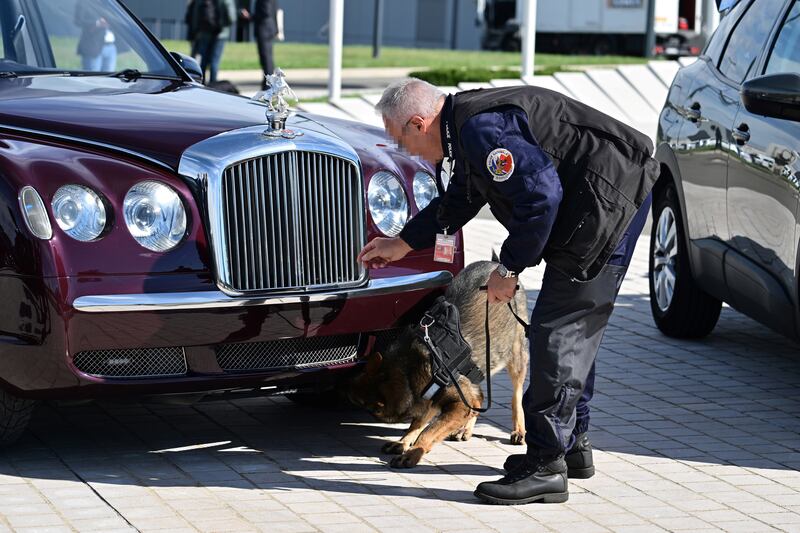 A bomb squad member and a sniffer dog inspect a car prior to the arrival of the king. EPA