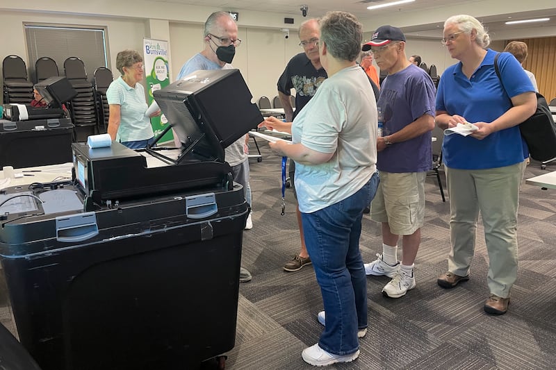 An election judge shows people how the voting machine will operate and detect errors on ballots on election day at a polling centre in Burnsville, Minnesota. AP