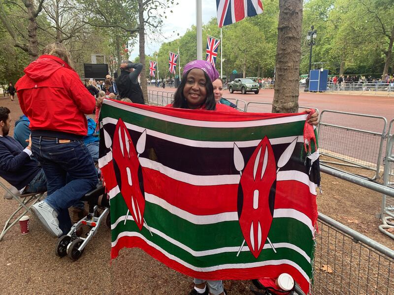 Esther Ravenor holds up a Kenyan flag while waiting to watch the queen's coffin pass by along The Mall. Photo: The National