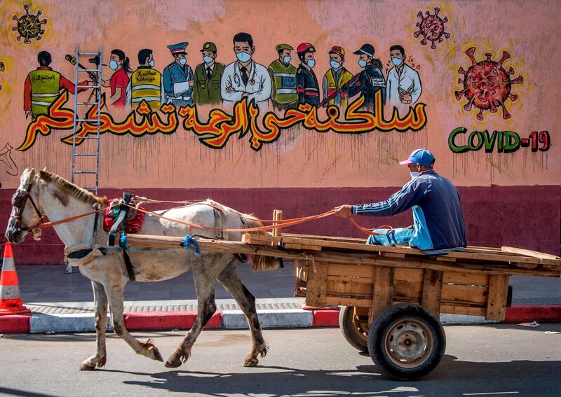 A Moroccan man drives his horse-drawn cart past a mural thanking essential workers amid the Covid-19 pandemic, in the city of Sale north of the capital. AFP