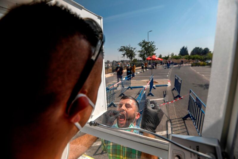 A paramedic of Israel's national emergency department collects a swab sample from a Palestinian man at a mobile testing station for the coronavirus, in the Arab neighbourhood of Sheikh Jarrah in the occupied east Jerusalem.  AFP