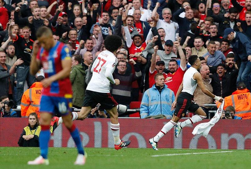 Manchester United’s English midfielder Jesse Lingard (R) pulls off his shirt as he celebrates scoring their second goal in extra time during the English FA Cup final football match between Crystal Palace and Manchester United at Wembley stadium in London on May 21, 2016. Manchester United won the game 2-1, after extra time. Adrian Dennis / AFP