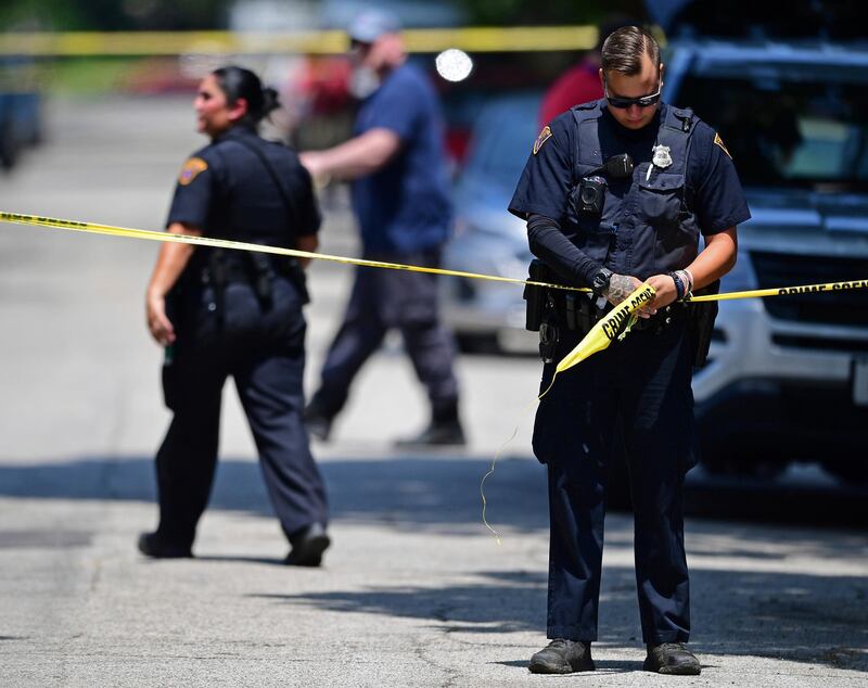 A police officer tapes off the crime scene where several bodies were found, Tuesday, July 9, 2019, in Cleveland. Police investigating the shooting death of a man in a vacant lot say they also found the bodies of a woman and two children in a nearby house. Authorities aren't saying how the three found inside the house Tuesday died, but they did say the four deaths are connected. (AP Photo/David Dermer)