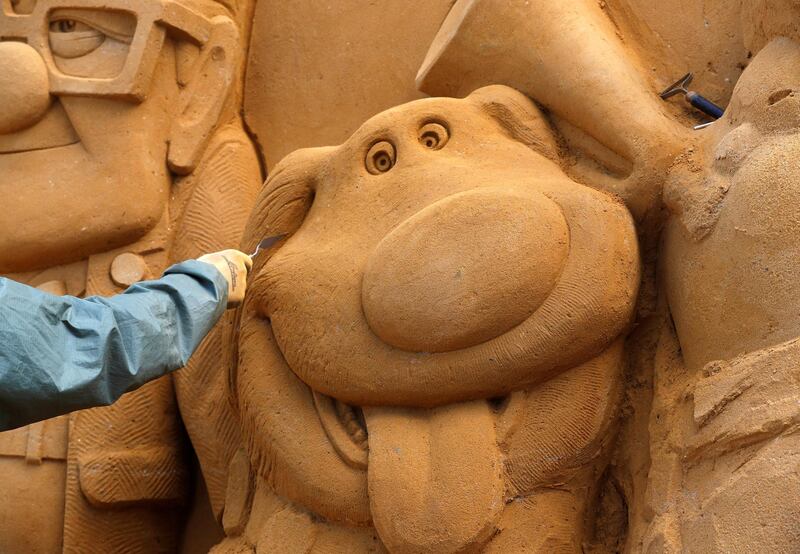 A sand carver works on a sculpture from the Disney film 'Up' during the Sand Sculpture Festival. Yves Herman / Reuters