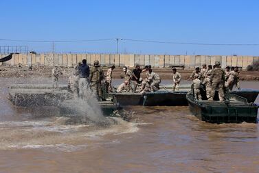 (FILES) In this file photo taken on March 06, 2017 international coalition forces and Iraqi soldiers instal a floating bridge at the Taji camp, north of Baghdad, during a training session. Katyusha rockets targeted an Iraqi airbase north of Baghdad hosting US-led coalition forces, the Iraqi military said on January 14, 2020 in the latest attack on installations where American troops are deployed. The statement from Iraq's military did not say how many rockets had hit Camp Taji but reported that there were no casualties. / AFP / SABAH ARAR