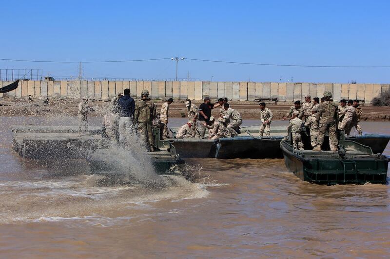 (FILES) In this file photo taken on March 06, 2017 international coalition forces and Iraqi soldiers instal a floating bridge at the Taji camp, north of Baghdad, during a training session. Katyusha rockets targeted an Iraqi airbase north of Baghdad hosting US-led coalition forces, the Iraqi military said on January 14, 2020 in the latest attack on installations where American troops are deployed. The statement from Iraq's military did not say how many rockets had hit Camp Taji but reported that there were no casualties. / AFP / SABAH ARAR

