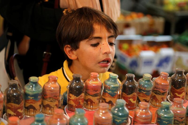 A boy looks at sand artworks at Al-Awawda's shop. Reuters