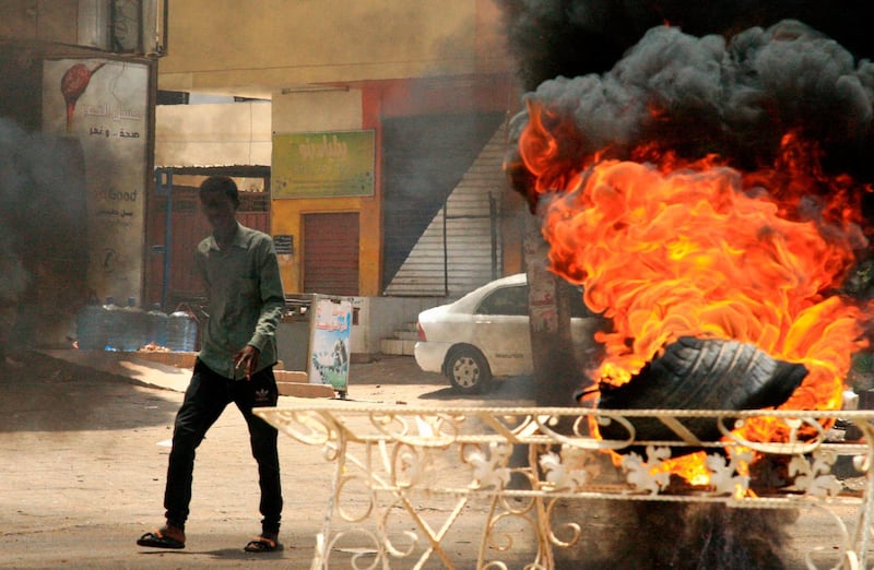 A Sudanese protester walks past a burning tyre near Khartoum's army headquarters after security forces broke up a weeks-long sit-in. AFP