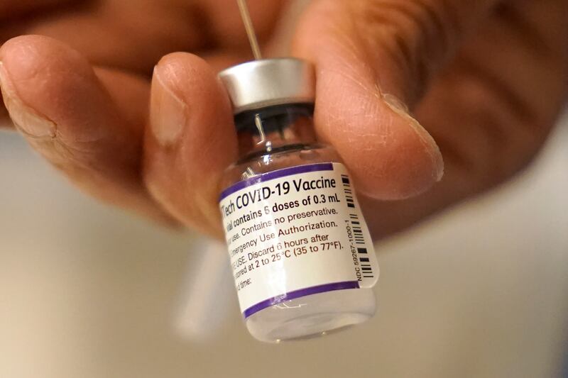 Dr Manjul Shukla transfers a dose of the Pfizer-BioNTech Covid-19 vaccine into a syringe at a mobile clinic in Worcester, Massachusetts.  As the US recorded its first confirmed case of the Omicron variant, doctors across the country are experiencing a surge in infections and the number of people being admitted to hospital in New England and the Midwest. AP