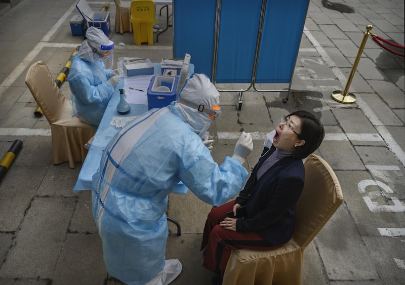 A Chinese health worker carries out a nucleic acid test on a journalist covering events around the National People's Congress. Getty