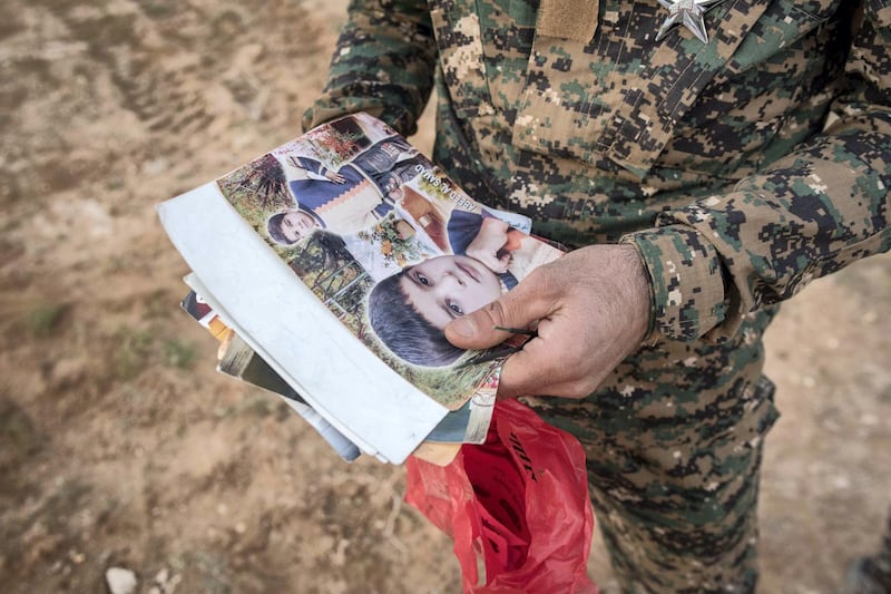 A Syrian Democratic Forces fighter searches the possessions of civilians who fled the last pocket of ISIS territory in Syria outside Baghouz, 28 February 2019. Campbell MacDiarmid