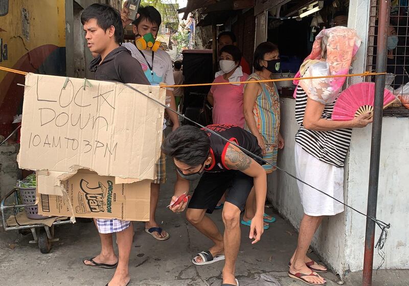 People cross a makeshift barrier in Las Pinas, south of Manila, Philippines.  EPA