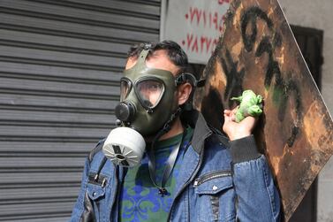 A masked Iraqi anti-government protester carries a makeshift shield at Al-Sinek bridge in the capital Baghdad on January 25, 2020. AFP