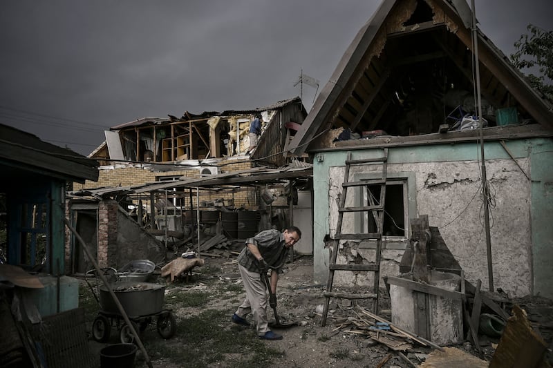 A man picks up debris after his house was destroyed by shelling in the city of Dobropillia, Donbas region. AFP