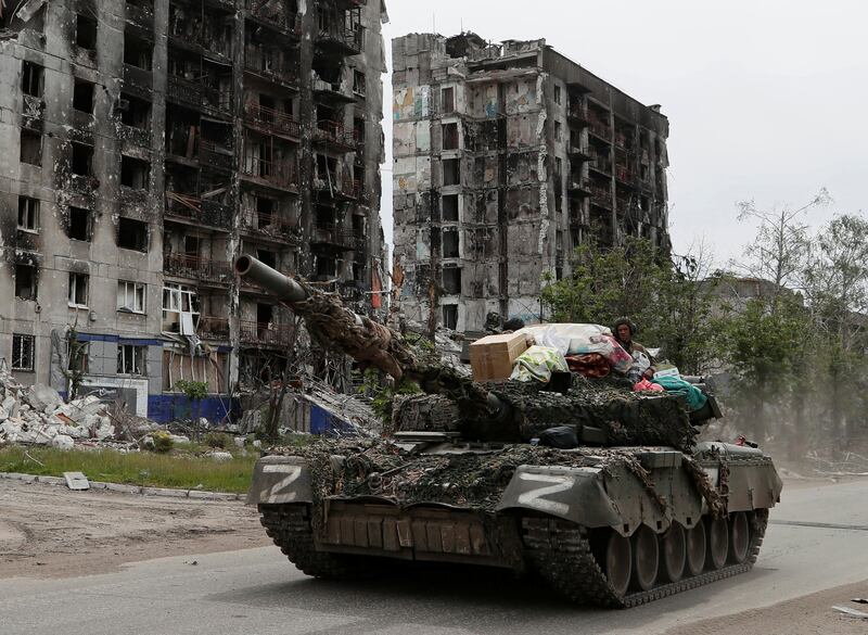 Service members of pro-Russian troops drive a tank past a destroyed residential building in the town of Popasna in the Luhansk region, Ukraine. Reuters