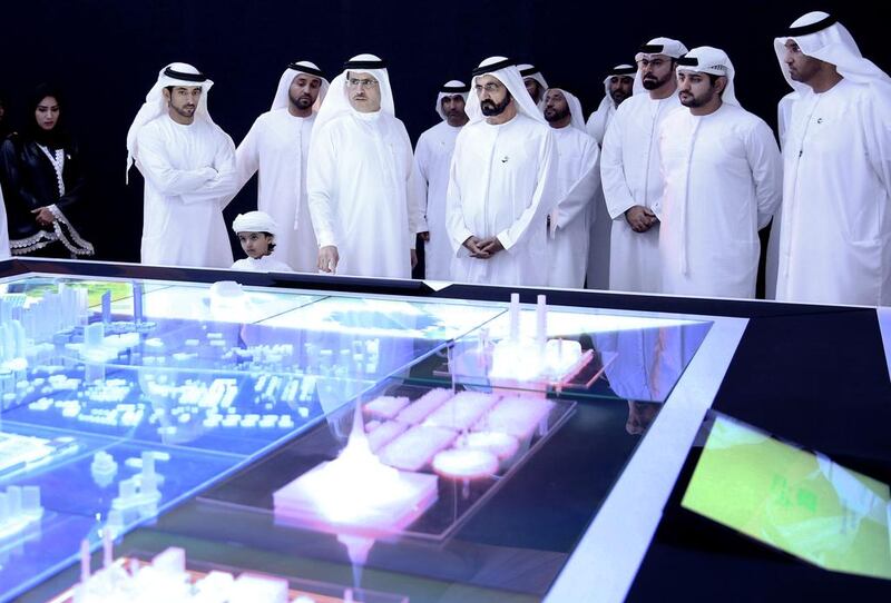 Sheikh Mohammed bin Rashid, centre, inspects a model of a solar plant. He has the same tendency as a leader to micro-monitor projects as his father did. Reuters