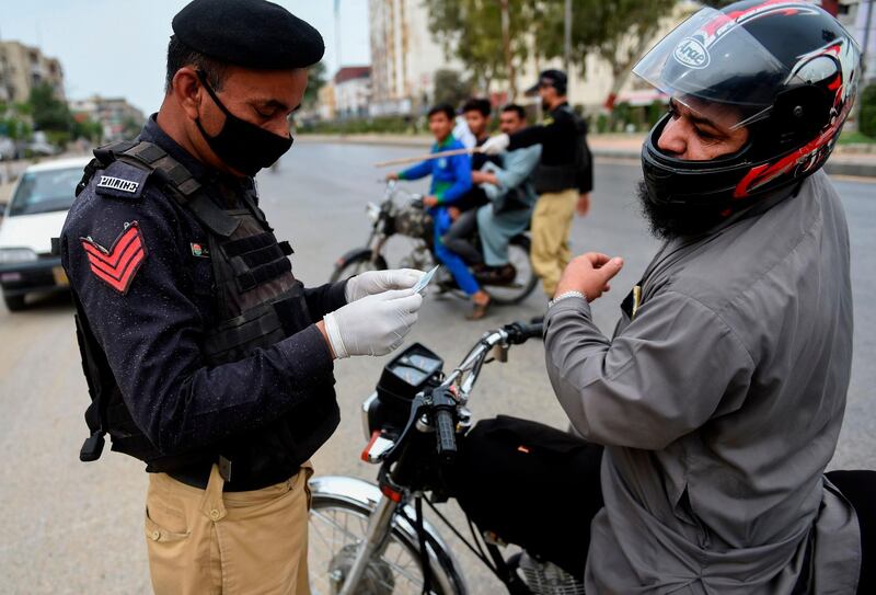 Policeman checks an identity card of a motorcyclist during a lockdown after Sindh province government announced the closing of markets, public places and ban large gatherings amid concerns over the spread of the COVID-19 novel coronavirus, in Karachi on March 23, 2020.  / AFP / Rizwan TABASSUM
