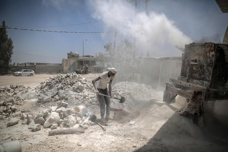 Workers with the rubble of buildings destroyed during the May rocket attacks. Sanad Latefa for The National