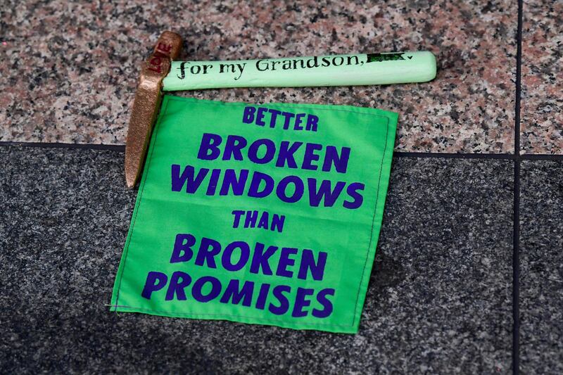 A slogan reading 'Better Broken Windows Than Broken Promises' is displayed during the protest. Reuters