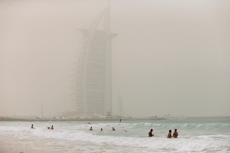 DUBAI, UAE. March 16, 2014- Beachgoers enjoy the cool water at Umm Suqiem Beach as the Burj Al Arab is cloaked in dust in Dubai, March 16, 2014. (Photo by: Sarah Dea/The National, Story by: STANDALONE, News)
