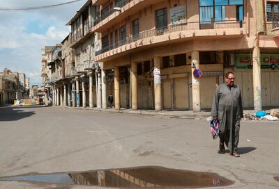 A man walks past shops that are shuttered to help prevent the spread of the coronavirus, in central Baghdad, Iraq, Sunday, March 22, 2020. Iraq announced a weeklong curfew to help fight the spread of COVID-19. (AP Photo/Hadi Mizban)