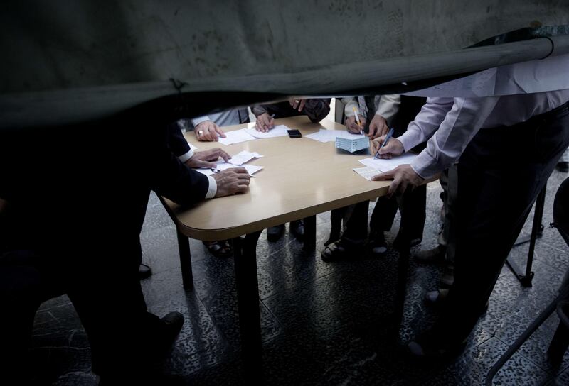 Iranians fill in their paper ballots as they vote in the first round of the presidential election at a polling station in southern Tehran on June 14, 2013. Iranians are voting to choose a new president in an election the reformists hope their sole candidate will win in the face of divided conservative ranks, four years after the disputed re-election of Mahmoud Ahmadinejad. AFP PHOTO/BEHROUZ MEHRI
 *** Local Caption ***  341323-01-08.jpg