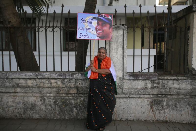 A woman stands draped in the Indian flag holding up a sign for Sachin. Rafiq Maqbool / AP