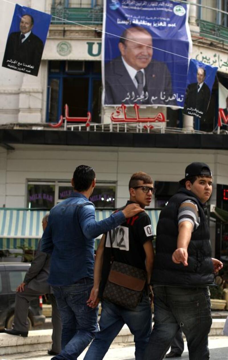 Algerian youths walk past posters of Algerian president Abdelaziz Bouteflika and other candidates in the  presidential elections, in the center of Algiers on April 15. Patrick Baz / AFP Photo