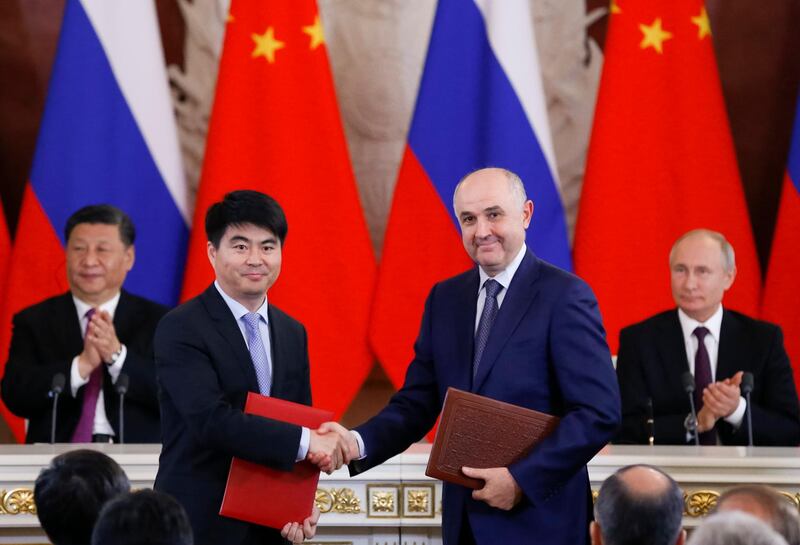 Guo Ping, deputy Chairman of Huawei Technologies Co Ltd, foreground left, shakes hands with Russian President of MTS mobile network operator, Alexei Kornya as Russian President Vladimir Putin, right, and Chinese President Xi Jinping attend a signing ceremony following their talks in the Kremlin in Moscow, Russia, Wednesday, June 5, 2019. Chinese President Xi Jinping is on visit to Russia this week and is expected to attend Russia's main economic conference in St. Petersburg. (AP Photo/Alexander Zemlianichenko, Pool)