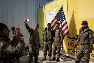 Syrian Democratic Forces (SDF) fighters pose for a photo with the American flag on stage after a SDF victory ceremony announcing the defeat of ISIS in Baghouz was held at Omer Oil Field on March 23, 2019 in Baghouz, Syria. Getty