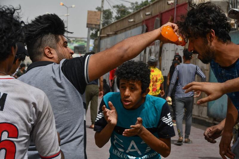 Iraqi protesters affected by smoke grenades receive help amid clashes with security forces following an anti-government demonstration in Iraq's southern city of Nasiriyah in Dhi Qar province.  AFP