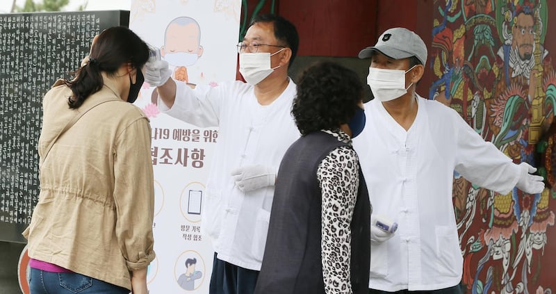 Officials of a Buddhist temple check congregants' temperatures before allowing entry to a temple on South Korea's southern resort island of Jeju, South Korea.  EPA