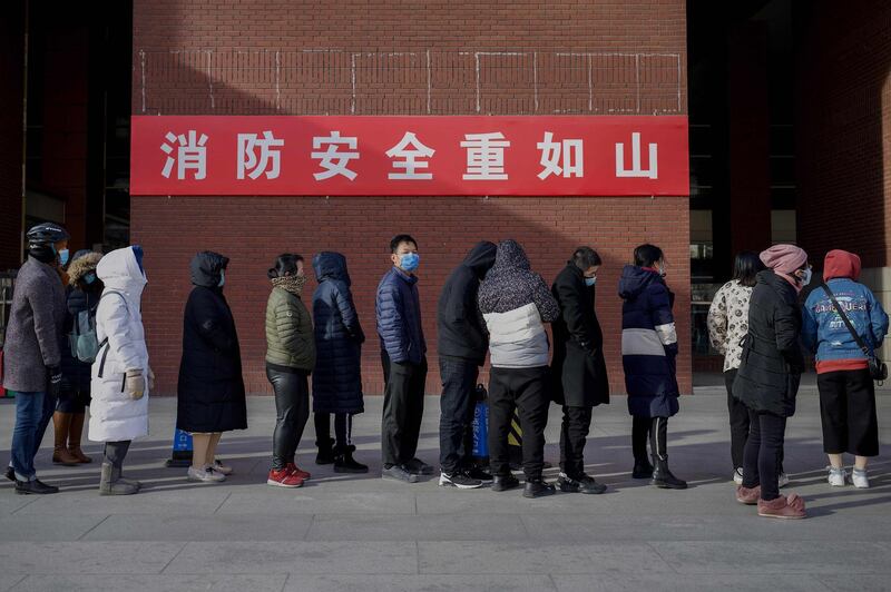 Residents wearing face masks wait in a queue to be tested for the Covid-19 coronavirus in Beijing. AFP