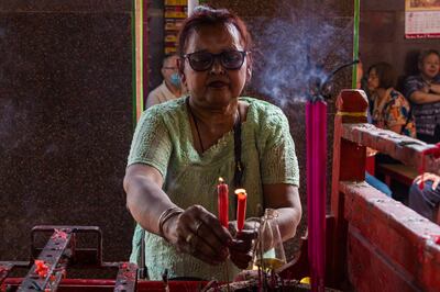 A lady lights candles in the temple courtyard