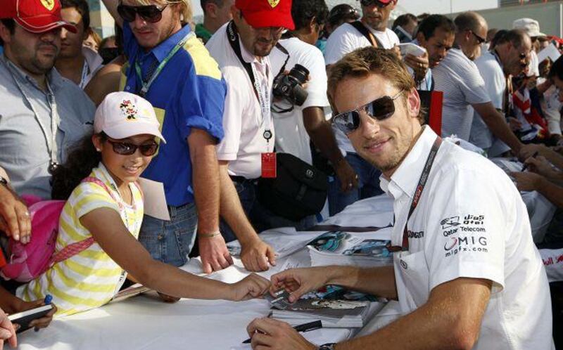 The Formula One driver Jenson Button signs autographs for fans on the pit lane walk last October.