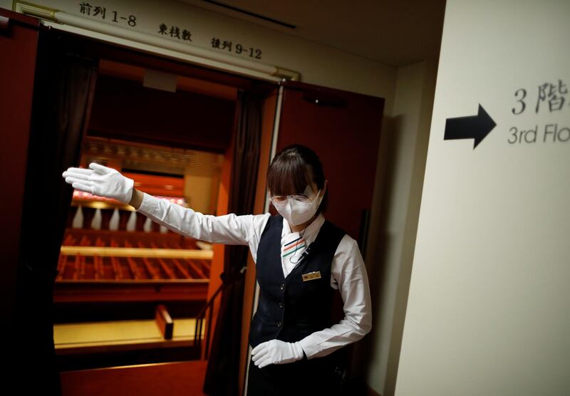 A staff member wearing protective face mask and shield shows directions at the Kabukiza Theatre. Reuters