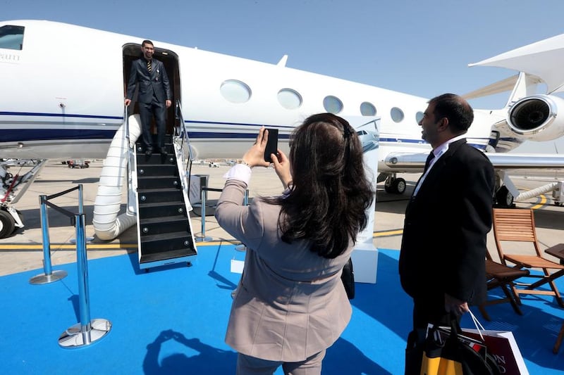 A visitor poses for a photo souvenir on the stair at a General Dynamics Gulfstream jet during the Abu Dhabi Air Expo. Fatima Al Marzooqi / The National