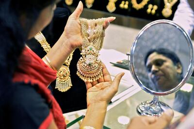 An Indian customer looks at gold jewellery at a stall in the Asia Jewels Fair 2017 held in Bangalore on August 11, 2017.  / AFP PHOTO / MANJUNATH KIRAN