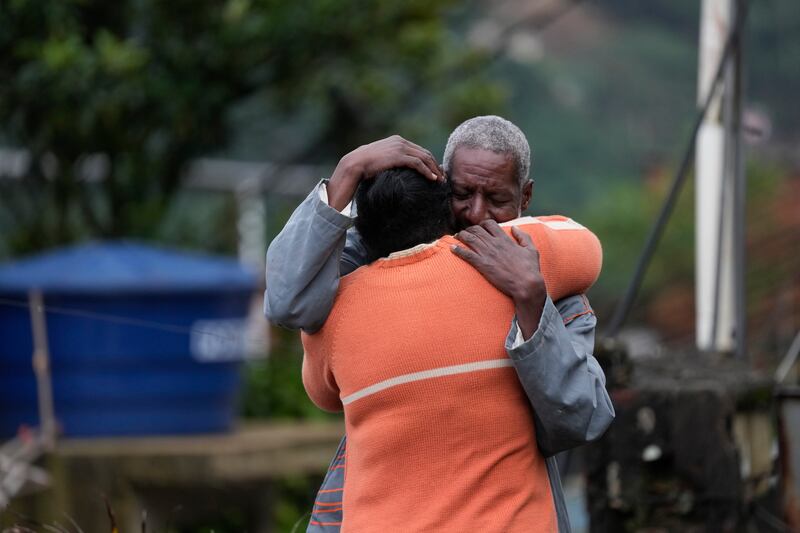 Residents embrace as they wait for a report on missing relatives. AP